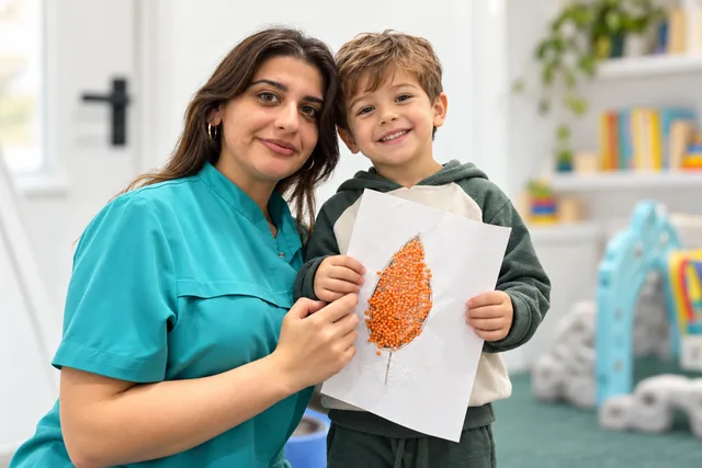 Firuzəyi geyimli pedaqoq və payız əl işi tutan uşaq.
